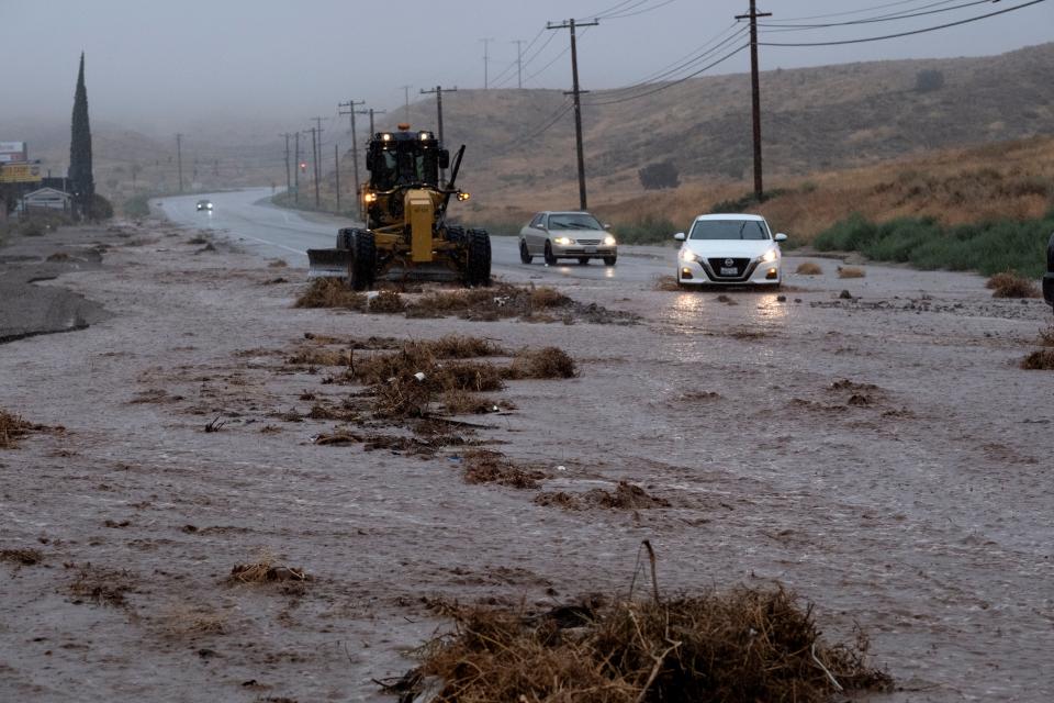 Cars maneuver around a plow clearing debris along a flooded Sierra Highway in Palmdale, Calif., as Tropical Storm Hilary moves through the area on Sunday, Aug. 20, 2023. (AP Photo/Richard Vogel)