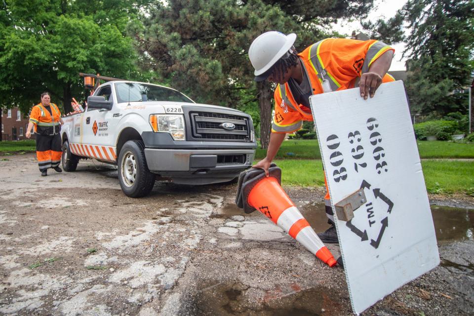 Janelle McCullough, 24, with Traffic Management, clears cones after a flash storm around the Grandmont neighborhood in Detroit on Wednesday, June 1, 2022. 