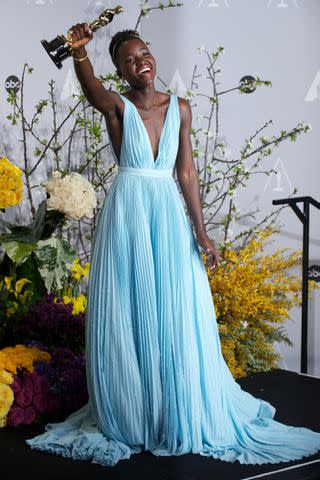 <p>Paul Bersebach/Digital First Media/Orange County Register via Getty</p> Lupita Nyong'o poses with her Oscar, outfitted in Prada, at the 2014 Oscars.