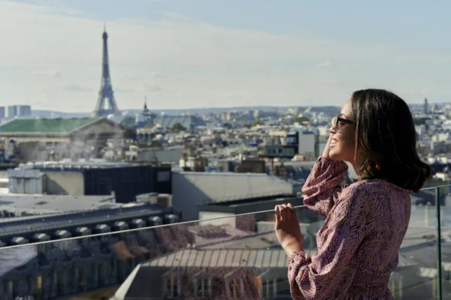 Турист гледа во Ајфеловата кула од покривот, Париз, Франција