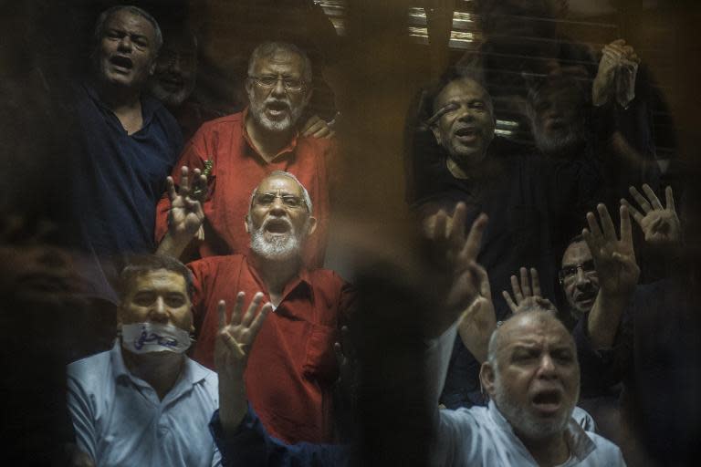 Egyptian Muslim Brotherhood leader Mohamed Badie (centre) gestures from behind the defendant's cage in Cairo on May 16, 2015