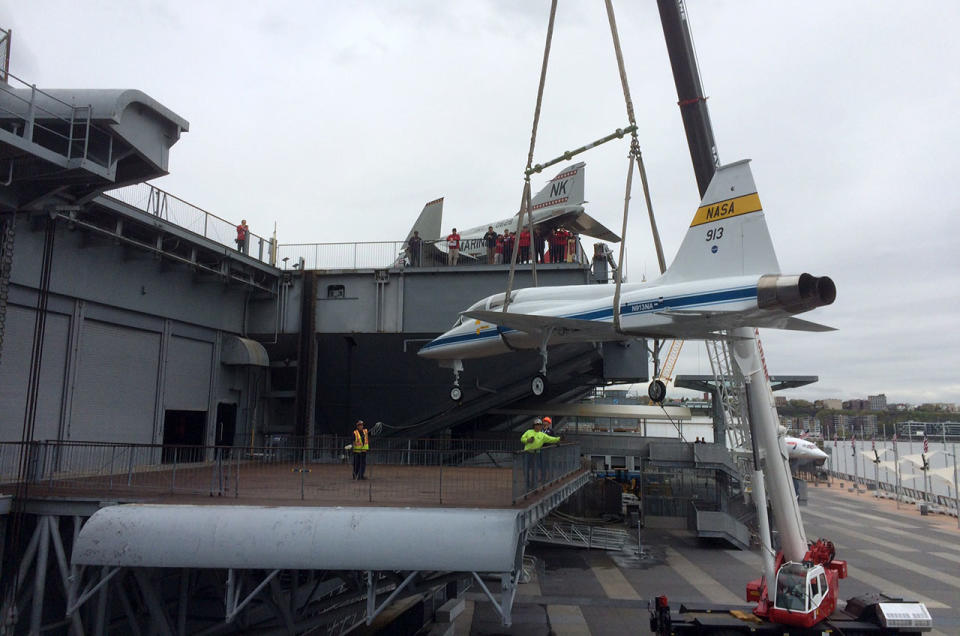 A crane hoists the NASA T-38 Talon jet, tail number 913, up onto the port side aircraft elevator of the Intrepid Sea, Air and Space Museum in New York City.