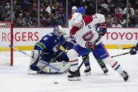 Vancouver Canucks goalie Collin Delia (60) watches as Montreal Canadiens' Nick Suzuki (14) skates with the puck during the second period of an NHL hockey game in Vancouver, British Columbia, Monday, Dec. 5, 2022. (Darryl Dyck/The Canadian Press via AP)