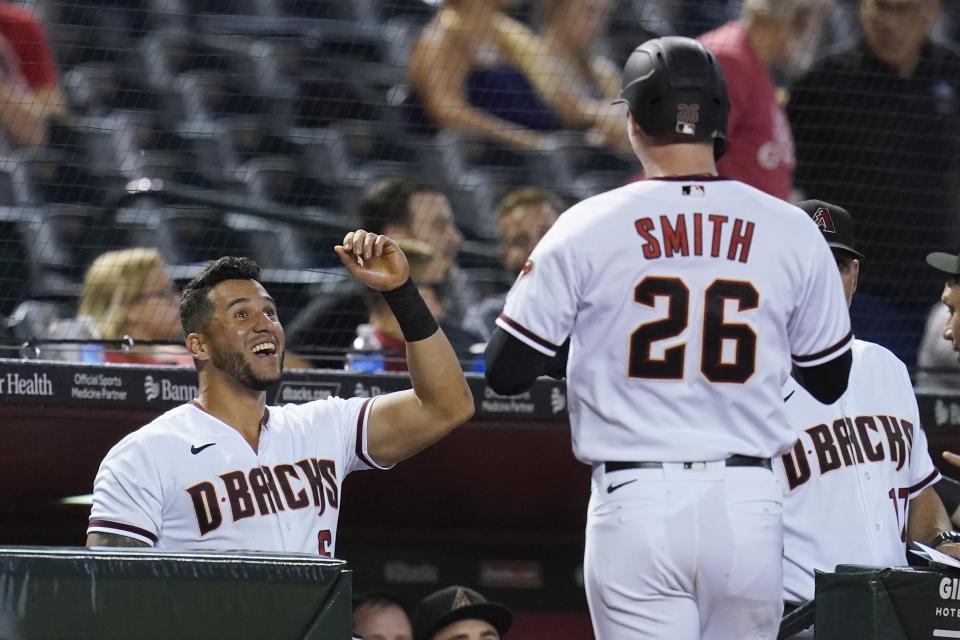 Arizona Diamondbacks' Pavin Smith (26) returns to the dugout after his home run against the San Francisco Giants to congratulations from David Peralta, left, during the fifth inning of a baseball game Thursday, July 1, 2021, in Phoenix. (AP Photo/Ross D. Franklin)