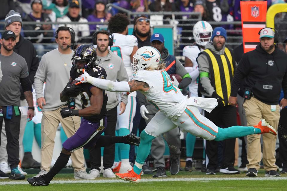 Dec 31, 2023; Baltimore, Maryland, USA; Baltimore Ravens running back Justice Hill (43) gains yardage in the third quarter defended by Miami Dolphins linebacker Andrew Van Ginkel (43) at M&T Bank Stadium. Mandatory Credit: Mitch Stringer-USA TODAY Sports