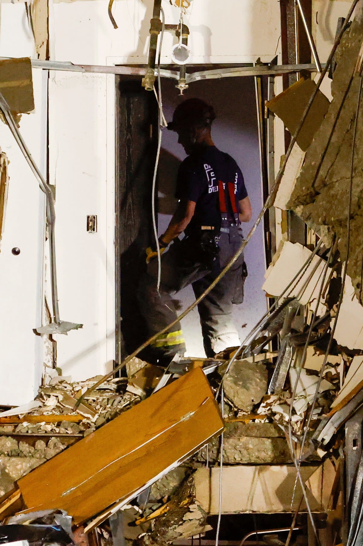 A firefighter combs through the wreckage while searching for residents potentially trapped after the collapse (AP)