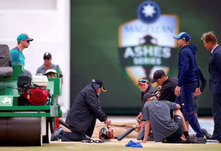 Cricket - Ashes test match - Australia v England - WACA Ground, Perth, Australia, December 18, 2017. England's captain Joe Root talks with Australia's captain Steve Smith as they inspect the pitch near ground staff using blowers as rain delays the start of play on the fifth day of the third Ashes cricket test match. REUTERS/David Gray