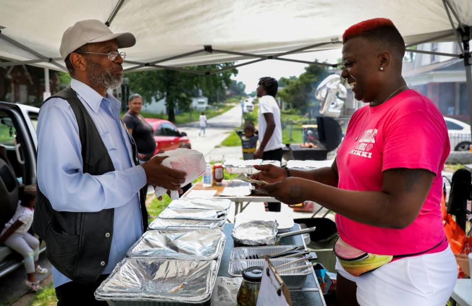 Nikki Howard jokes with Frank Dunbar as she gives him his food from a stand she runs on Genevieve Avenue in the Walnut Park neighborhood of St. Louis on Thursday, July 22, 2021. Nikki lived on Genevieve until 2015 after she and her son were shot in front of an abandoned property on the street. Photo by Colter Peterson, cpeterson@post-dispatch.com