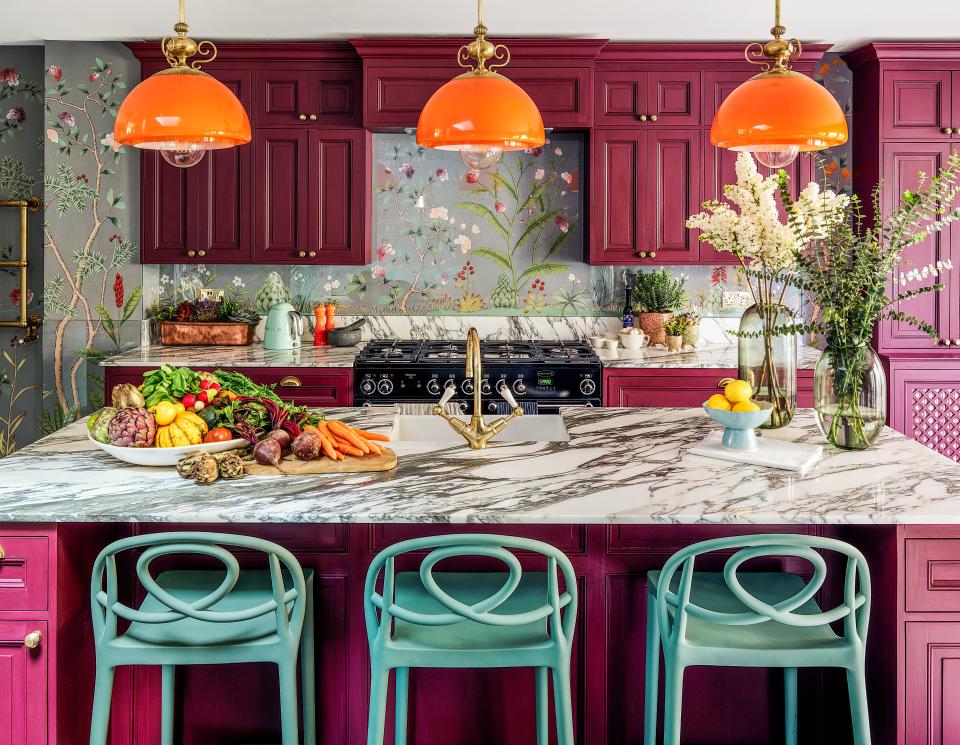 An arabescato marble island commands the kitchen. On cabinetry, custom magenta shade by Papers and Paints; Rangemaster range; de Gournay embroidered silk wall covering; antique billiard table pendants.