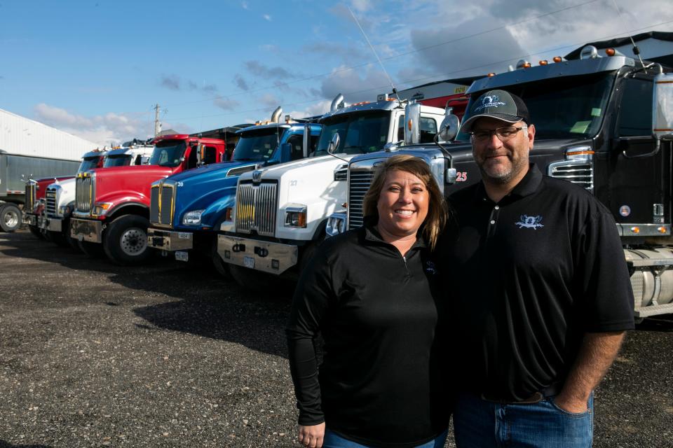 Corey and Katie Allen, owners of Callen Trucking, stand in front of a row of their dump trucks at Callen Trucking on April 3, 2024, in Lancaster, Ohio.