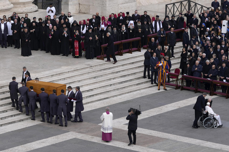 Pope Francis is pushed away on a wheelchair, right, while the coffin of late Pope Emeritus Benedict XVI is carried away after a funeral mass in St. Peter's Square at the Vatican, Thursday, Jan. 5, 2023. Benedict died at 95 on Dec. 31 in the monastery on the Vatican grounds where he had spent nearly all of his decade in retirement. (AP Photo/Ben Curtis)
