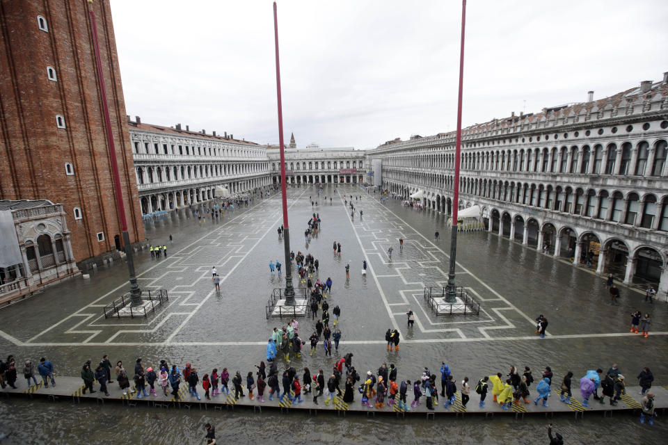 People walk on catwalk set up in a flooded St. Mark's Square, in Venice, Italy, Tuesday, Nov. 12, 2019. (Photo: Luca Bruno/AP)