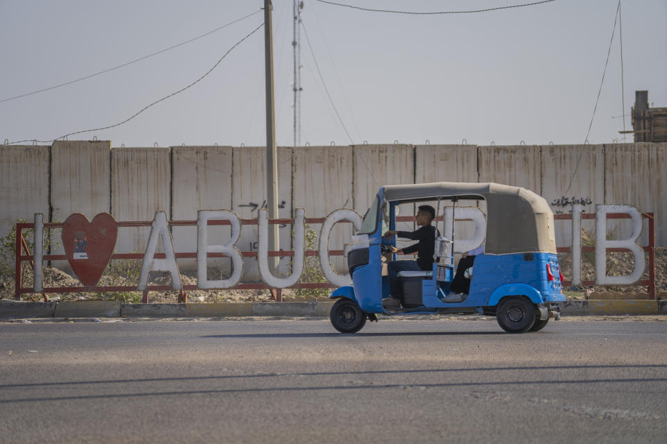 A motorized rickshaw, or tuk tuk, rides past the entrance of Abu Ghraib, Iraq, west of Baghdad, on Thursday, March 2, 2023. For Iraqis, the war and U.S. occupation which started two decades ago were traumatic – an estimated 300,000 Iraqis were killed between 2003 and 2019, according to an estimate by the Watson Institute for International and Public Affairs at Brown University, in addition to some 4,000 Americans. (AP Photo/Jerome Delay)
