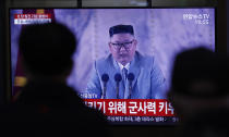 People wearing face masks watch a TV screen during a news program reporting about the ceremony to mark the 75th founding anniversary of the North Korea's ruling Workers' party, at the Seoul Railway Station in Seoul, South Korea, Saturday, Oct. 10, 2020. A part of letters read "Military strength." and A military parade to mark the 75th founding anniversary of the North Korea's ruling Workers' party. (AP Photo/Lee Jin-man)