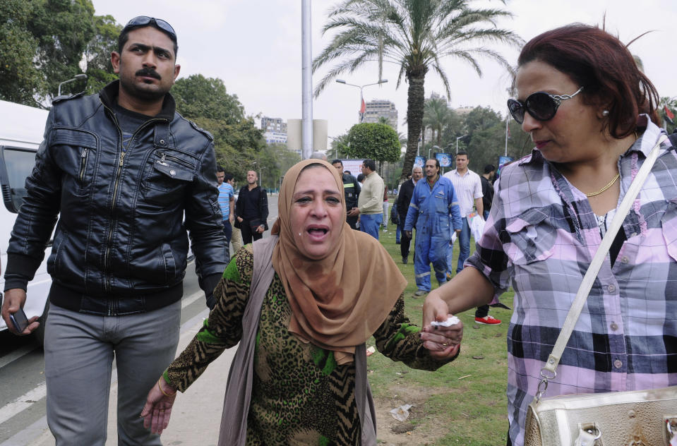An Egyptian woman, center, is escorted out of the site of multiple bombings outside the main campus of Cairo University in Giza, near downtown Cairo, Egypt, Wednesday, April 2, 2014. The bombings targeted riot police routinely deployed at the location in anticipation of near-daily protests by students who support ousted Islamist President Mohammed Morsi and his Muslim Brotherhood group. (AP Photo/Mohammed Asad)