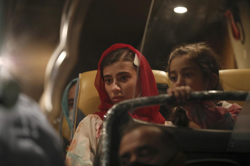 Afghan evacuees from Afghanistan sit in a bus after the arrival of the second flight with 95 passengers at the International Airport in Tirana, Albania, Friday, Aug. 27, 2021. Albania on Friday housed its first group of Afghan evacuees who made it out of their country despite days of chaos near the Kabul airport, including an attack claimed by the Islamic State group. (AP Photo/Franc Zhurda)