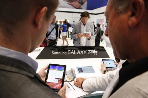 This file illustration photo shows visitors trying out a Samsung's Galaxy tablet computer during an electronic fair in Berlin, in September. Catching up on news is among the most popular activities for tablet computer owners, but most are not willing to pay for it, according to a study published on Tuesday