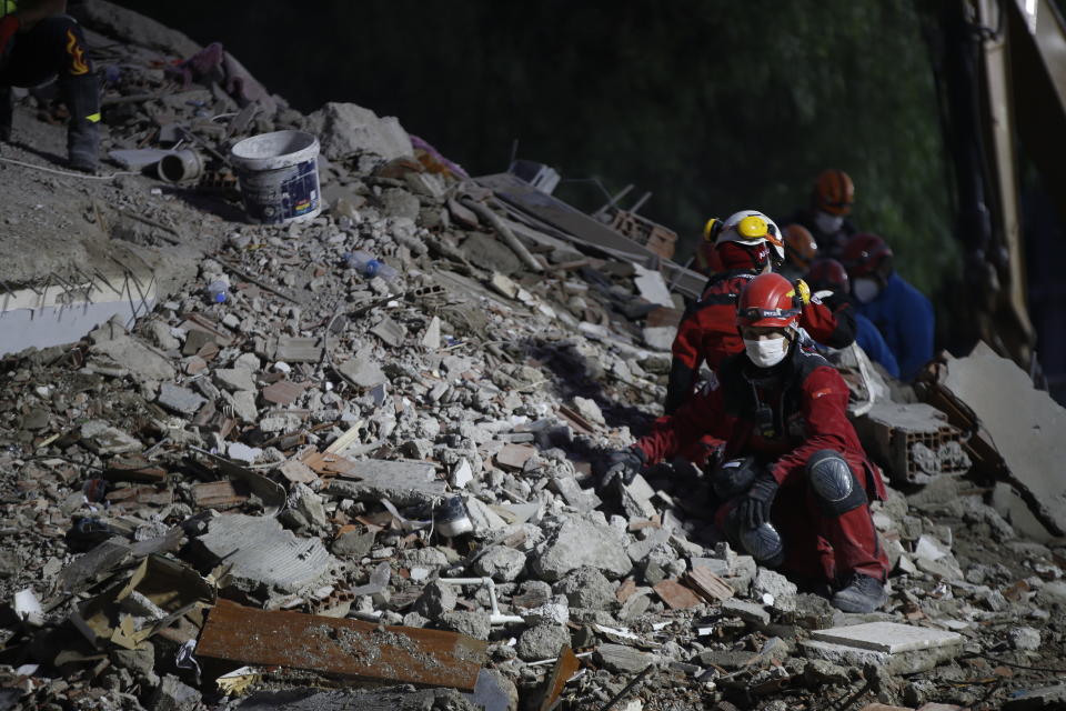 Members of rescue services sit in silence as they search in the debris of a collapsed building for survivors in Izmir, Turkey, Sunday, Nov. 1, 2020. Rescue teams continue ploughing through concrete blocs and debris of collapsed buildings in Turkey's third largest city in search of survivors of a powerful earthquake that struck Turkey's Aegean coast and north of the Greek island of Samos, Friday Oct. 30, killing dozens Hundreds of others were injured.(AP Photo/Emrah Gurel)
