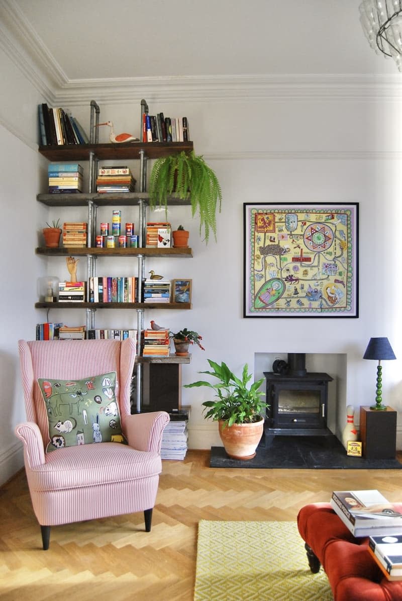 Living room with a lounge chair, fireplace, and floor-to-ceiling bookshelf.