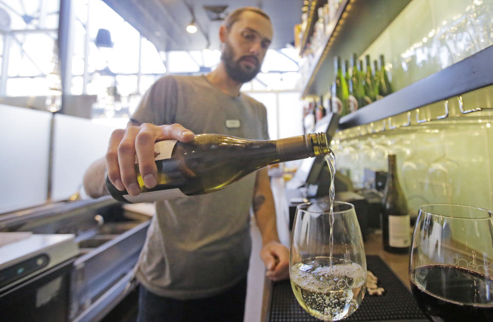 This Wednesday, March 29, 2017, photo, Current Fish & Oyster Restaurant bartender Wren Kennedy pours wine behind the bar, in Salt Lake City. At Current Fish & Oyster Restaurant, a frosted glass wall covering a long, glossy bar will come down at the stroke of midnight on July 1, according to Joel LaSalle, one of the restaurant's owners. "Not only is it ugly and covers up a beautiful bar, but it's costing us thousands of dollars in sales each month," Some Utah restaurants are counting down the days until a new liquor law takes effect this summer, allowing eateries to take stop using walls and partitions that prevent customers from seeing their alcoholic drink being mixed and poured. (AP Photo/Rick Bowmer)