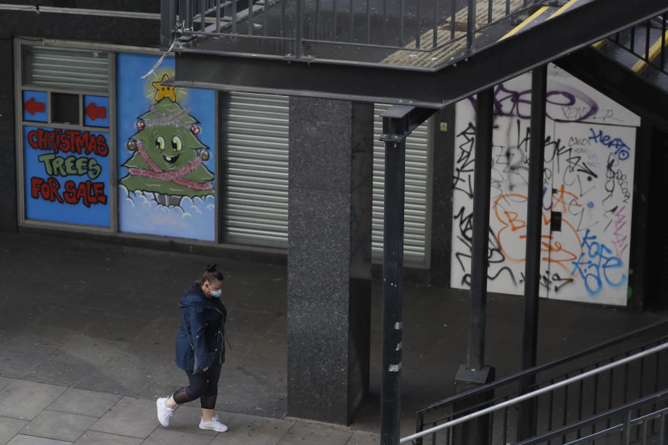 A woman walks by closed shops, in Waterloo in London, Saturday, Jan. 23, 2021 during England's third national lockdown since the coronavirus outbreak began. The U.K. is under an indefinite national lockdown to curb the spread of the new variant, with nonessential shops, gyms and hairdressers closed, and people being told to stay at home. (AP Photo/Kirsty Wigglesworth)