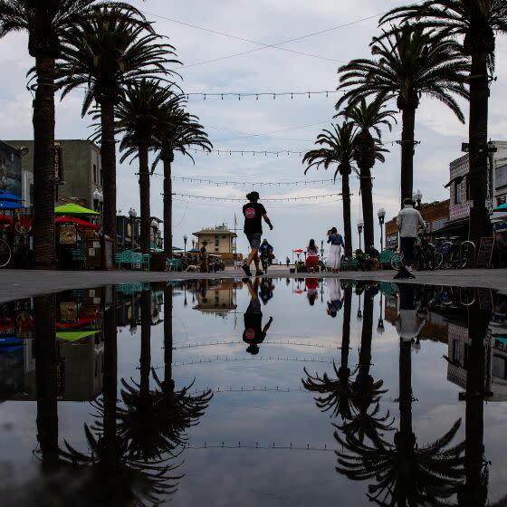 A pedestrian is reflected in a puddle in Hermosa Beach on Monday after rain passed through the area.