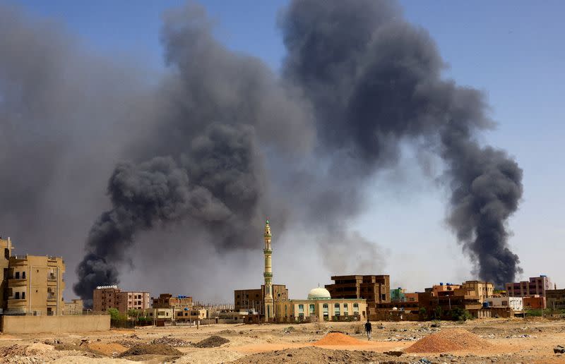 FILE PHOTO: Man walks while smoke rises above buildings after aerial bombardment in Khartoum North