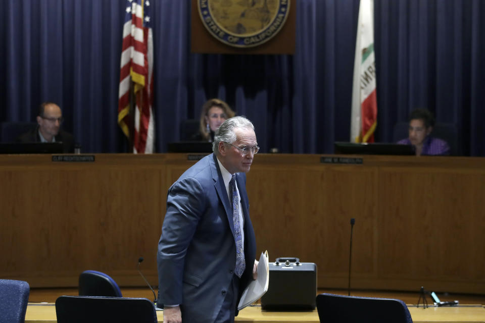 Pacific Gas and Electric Company (PG&E) CEO Bill Johnson, bottom, walks to his seat after speaking during a California Public Utilities Commission meeting in San Francisco, Friday, Oct. 18, 2019. (AP Photo/Jeff Chiu)