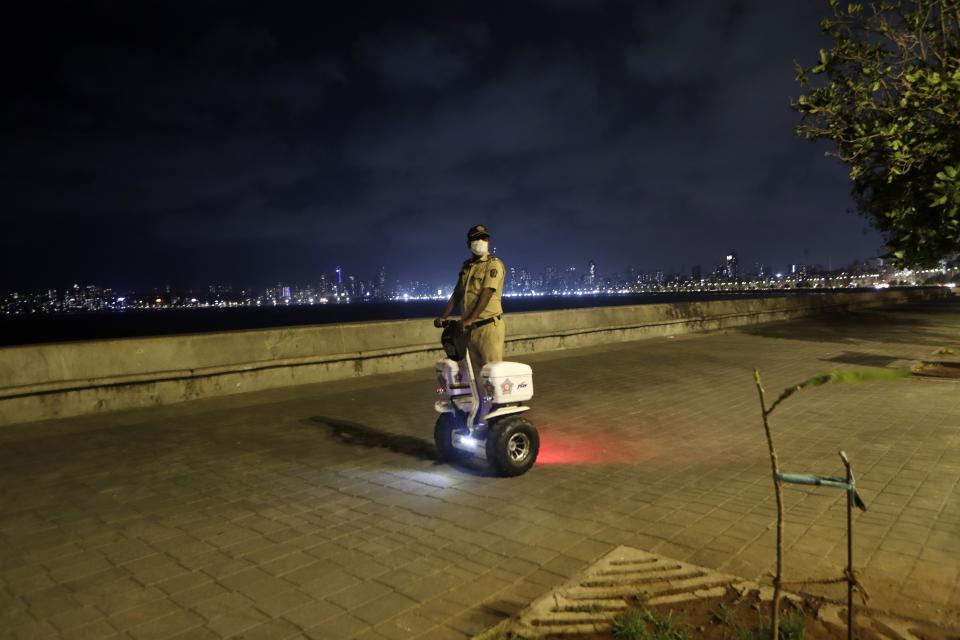 A security person patrols at the Marine Drive in Mumbai, India, Wednesday April 14, 2021. The teeming metropolis of Mumbai and other parts of Maharashtra, the Indian state worst hit by the pandemic, face stricter restrictions for 15 days starting Wednesday in an effort to stem the surge of coronavirus infections. (AP Photo/Rajanish Kakade)