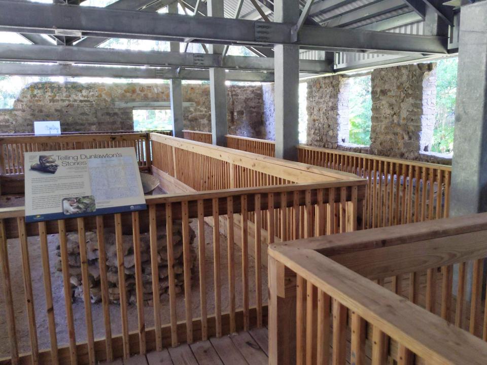 A wooden walkway with history placards under an arched wooden roof.