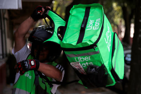 A man puts on a delivery bag with the logo of Uber Eats in Mexico City, Mexico May 20, 2019. REUTERS/Carlos Jasso