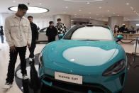 Visitors to the Xiaomi Automobile flagship store looks at the Xiaomi SU7 electric car on display in Beijing, Tuesday, March 26, 2024. Chinese smartphone maker Xiaomi announced that it will deliver its first electric vehicle on March 28, 2024. (AP Photo/Ng Han Guan)