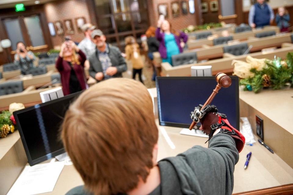 Gavin Sumner grips a gavel in the seat where Montgomery County Mayor Jim Durrett would normally sit during county commission meetings. Gavin was given mechanical hands Dec. 23, which make gripping the gavel one-handed possible.