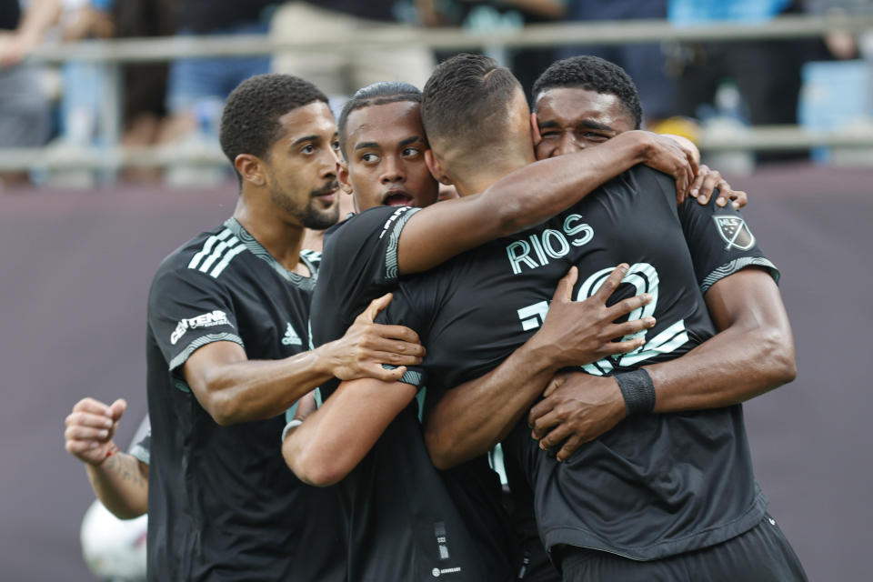 Charlotte FC players embrace forward Daniel Ríos after he scored the winning goal in the 85th minute in the second half against the Vancouver Whitecaps in an MLS soccer match in Charlotte, N.C., Sunday, May 22, 2022. (AP Photo/Nell Redmond)