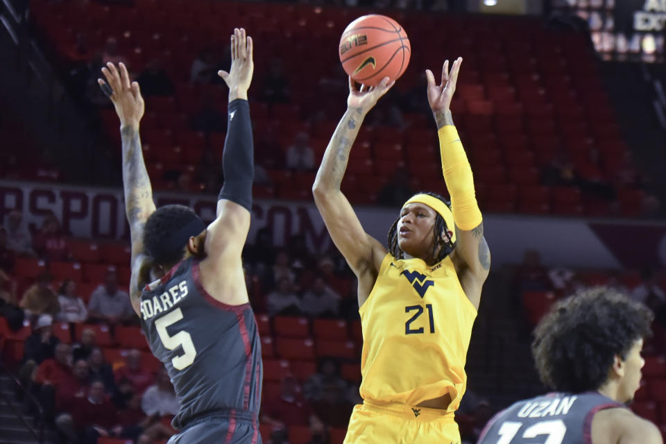 West Virginia guard RaeQuan Battle (21) shoots over Oklahoma guard Rivaldo Soares (5) during the second half of an NCAA college basketball game Wednesday, Jan. 17, 2024, in Norman, Okla. (AP Photo/Kyle Phillips)