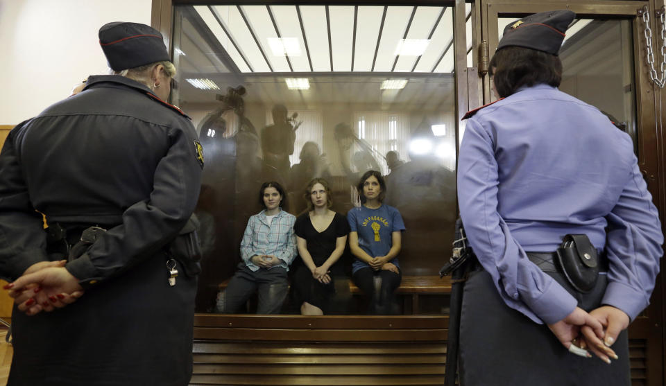 FILE - Feminist punk group Pussy Riot members, from left, Yekaterina Samutsevich, Maria Alekhina and Nadezhda Tolokonnikova sit in a defendants’ cage at a court in Moscow, Russia, Aug. 17, 2012. Over the last decade, Vladimir Putin's Russia evolved from a country that tolerates at least some dissent to one that ruthlessly suppresses it. Arrests, trials and long prison terms — once rare — are commonplace. (AP Photo, File)