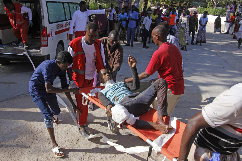 Medical personnel carry a civilian who was wounded in suicide car bomb attack at check point in Mogadishu, Somalia, Saturday, Dec, 28, 2019. A police officer says a car bomb has detonated at a security checkpoint during the morning rush hour in Somalia's capital. (AP Photo/Farah Abdi Warsame)