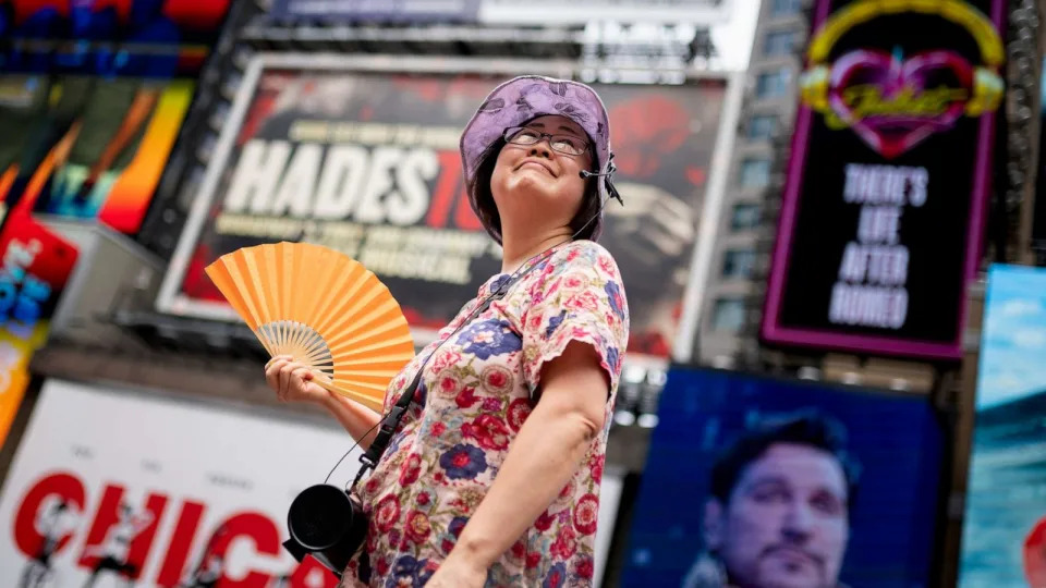 PHOTO: A tour guide fans herself while working in Times Square as temperatures rise, July 27, 2023, in New York City. (John Minchillo/AP)