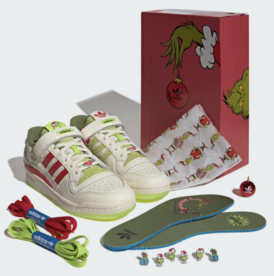 cream and green sneakers next to product box, shoe inserts, the grinch pins and red and green shoelaces