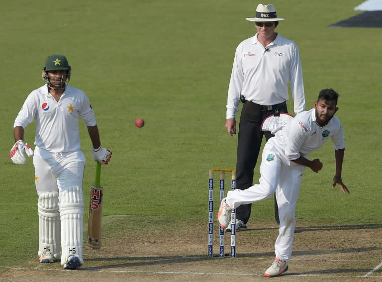 West Indies' spinner Devendra Bishoo (R) bowls Pakistani batsman Sarfraz Ahmed (L) looks on during the first day of the third and final Test at the Sharjah Cricket Stadium in Sharjah on October 30, 2016 Pakistan captain Misbah-ul-Haq won the toss and opted to bat against West Indies in the third and final Test in Sharjah
