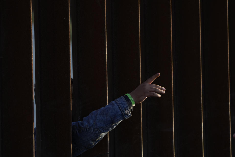 FILE- A man gestures as he waits with others to apply for asylum between two border walls Thursday, May 11, 2023, in San Diego. Asylum-seekers say joy over the end of the public health restriction known as Title 42 this month is turning into anguish with the realization of how the Biden administration's new rules affect them. Though the government opened some new avenues for immigration, many people's fate is largely left up to a U.S. government app that is limited and unable to decipher and prioritize human suffering and personal risk. (AP Photo/Gregory Bull)