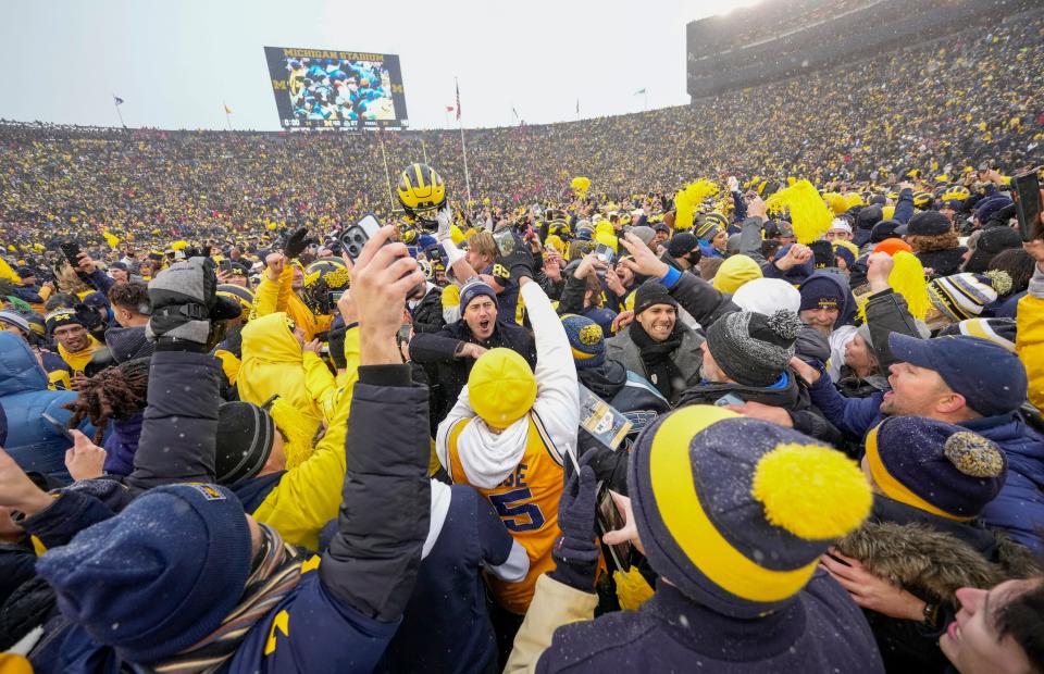 Michigan Wolverines fans storm the field following the NCAA football game against the Ohio State Buckeyes at Michigan Stadium in Ann Arbor on Sunday, Nov. 28, 2021. Ohio State lost 42-27.