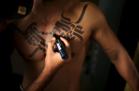 Palestinian artist Bilal Khalid paints Arabic letters on a bodybuilder in a gym in Gaza City April 12, 2016. REUTERS/Mohammed Salem