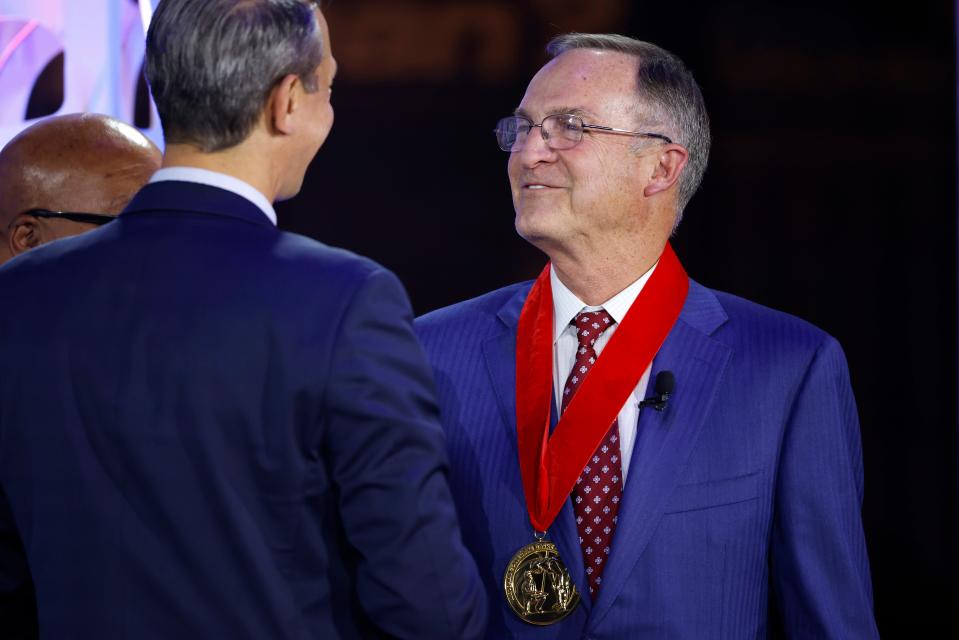 Former Kansas State, Florida, Illinois, UNLV and Oklahoma head coach Lon Kruger, right, reacts after receiving a medal during a National Collegiate Basketball Hall of Fame induction event Sunday in Kansas City, Mo.