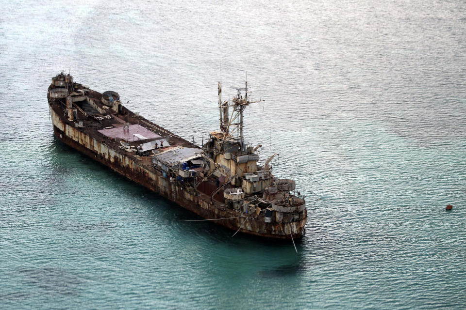 FILE - This areral photo taken through a glass window of a military plane shows the dilapidated Sierra Madre ship of the Philippine Navy anchored near Ayungin Shoal with Filipino soldiers onboard to secure perimeter in the Spratly Islands in the South China Sea on May 11, 2015. Chinese coast guard ships blocked and used water cannons on two Philippine supply boats heading to a disputed shoal occupied by Filipino marines in the South China Sea, provoking an angry protest against China and a warning from the Philippine government that its vessels are covered under a mutual defense treaty with the U.S., Manila’s top diplomat said Thursday, Nov. 18, 2021. (Ritchie B. Tongo/Pool Photo via AP, File)