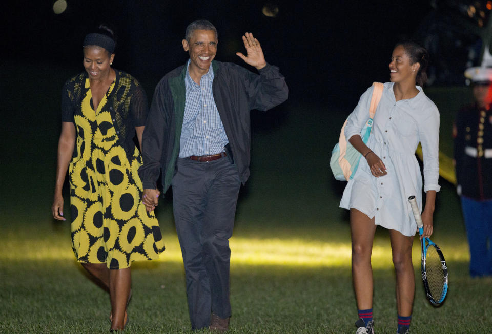 President Barack Obama and first lady Michelle Obama walk with their daughter Malia across the South Lawn of the White House in Washington, Sunday, Aug. 24, 2014, following their arrival on Marine One.