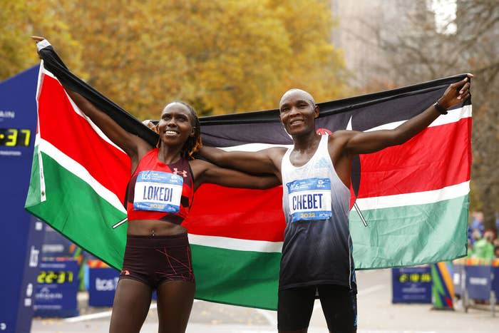 Women's division winner Sharon Lokedi and men's division winner Evans Chebet pose at the finish line of the New York City Marathon with Kenyan flags on Sunday.