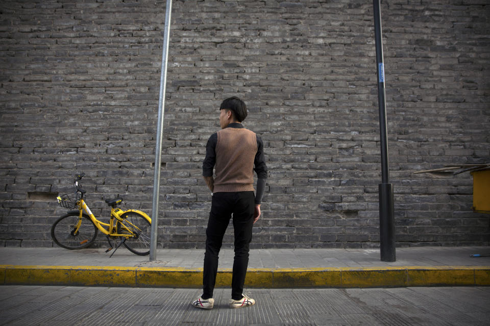 In this March 28, 2019, photo, Tylox user Yin Hao, who also goes by Yin Qiang, pauses while walking along a street near the old city walls in Xi'an, northwestern China's Shaanxi Province. Officially, pain pill abuse is an American problem, not a Chinese one. But people in China have fallen into opioid abuse the same way many Americans did, through a doctor's prescription. And despite China's strict regulations, online trafficking networks, which facilitated the spread of opioids in the U.S., also exist in China. (AP Photo/Mark Schiefelbein)