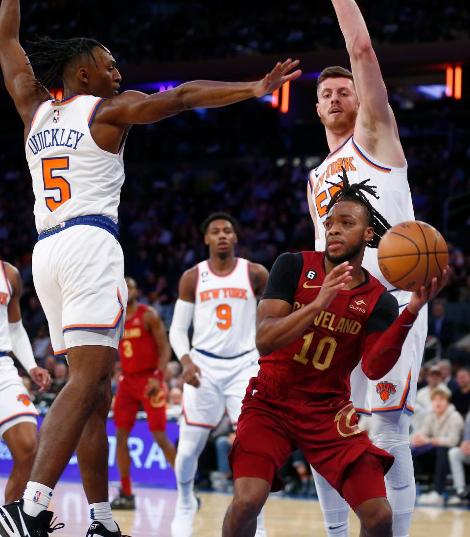 Cleveland Cavaliers guard Darius Garland (10) looks to pass while being defended by New York Knicks guard Immanuel Quickley (5) and center Isaiah Hartenstein, right, during the first half of an NBA basketball game, Sunday, Dec. 4, 2022, in New York. (AP Photo/John Munson)