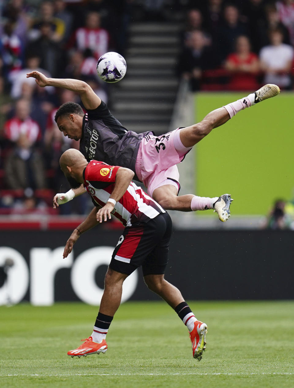 Brentford's Bryan Mbeumo, left, and Fulham's Antonee Robinson, top, battle for the ball during the English Premier League soccer match between Fulham FC and Brentford FC at the Gtech Community Stadium in London, Saturday May 4, 2024. (John Walton/PA via AP)